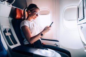 Woman on an airplane using Wifi on her phone