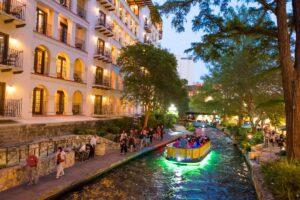 Boat ride through San Antonio River Walk in evening